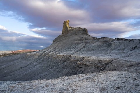 A stunning view of a uniquely shaped rock formation amid textured desert terrain in Utah, captured