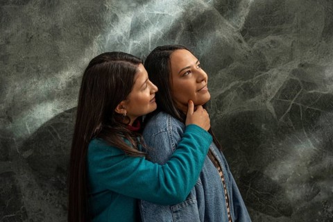 A Latin lesbian couple shares a loving embrace, expressing warmth and affection. The tender moment