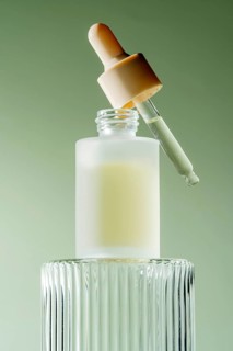 An elegant serum dropper bottle with a pipette resting on its rim, filled with a milky serum, set
