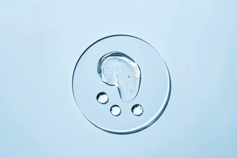 Transparent liquid droplets rest on a smooth, light surface The image showcases the purity and