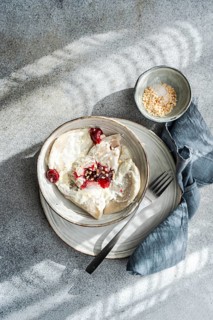 Boiled Ukrainian varenyky filled with cherry, served with a topping of sour cream and chopped nuts