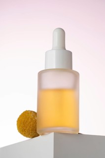 Elegantly displayed cosmetic serum bottle with a dropper, positioned on a geometric podium against