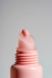 Close-up view of a pink lip balm on pink tube against a neutral background. This image showcases