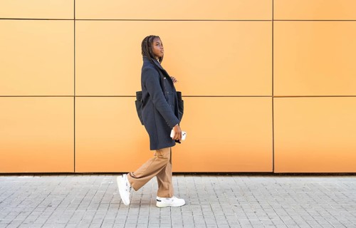 A young African American businesswoman with braids, dressed in a formal grey jacket and beige
