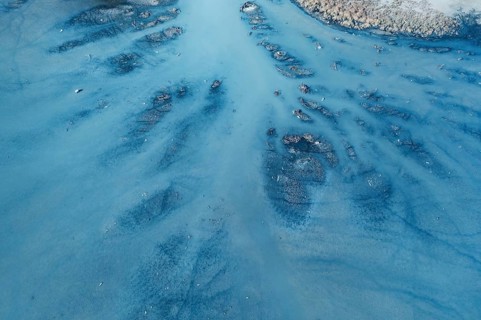An aerial view of a lagoon in Toledo, Spain, revealing intricate water channels and sediment