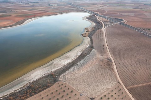 Aerial view of Toledo Lagoons, Spain, showcasing a serene lake amidst farmland. Home to diverse