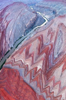 An aerial photograph captures the stunning Rio San Juan as it snakes through the vivid red and grey