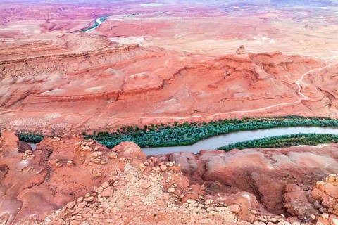 Aerial shot captures the serpentine Rio San Juan cutting through the vibrant red desert landscape