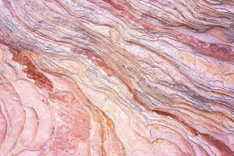 Close-up image showcasing the intricate patterns and warm hues of red rock formations that reveal