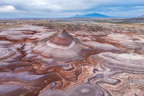 A captivating drone image of an unrecognizable person standing on the unique, multicolored rock