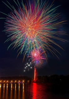 A stunning fireworks show illuminates the night sky above the Ebro River, casting vibrant