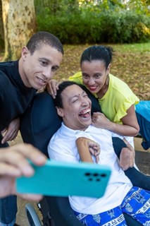 Two siblings pose for a joyful selfie with their disabled brother, who has cerebral palsy, enjoying