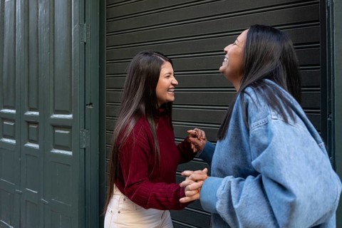 A joyful latin lesbian couple shares a moment of laughter and connection in front of a closed