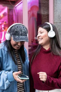 A latin lesbian couple enjoys music together with headphones. Smiling and relaxed, they share a