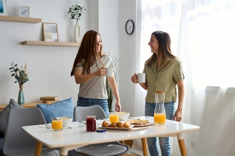 A lesbian couple shares a cozy morning breakfast at home They smile warmly at each other, holding
