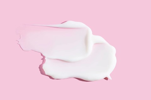 A delicate smear of creamy cosmetic product, displaying texture against a soothing pink background.