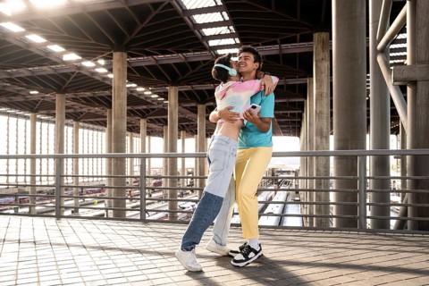 A joyful moment for a couple embracing each other at a train station. The sunlight filters through