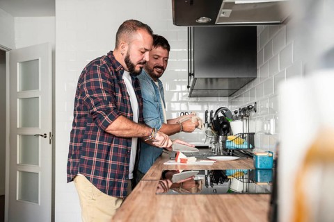 A joyful gay couple prepares a meal together in their modern kitchen, showcasing a harmonious