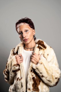 A woman with distinctive makeup and jewelry poses confidently looking at camera in a stylish faux