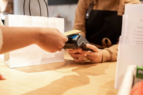 A customer makes a purchase using a point-of-sale terminal in a cosmetics store. A paper shopping