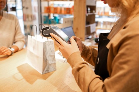 A retail worker processes a transaction at a cosmetics store. The scene captures the sale