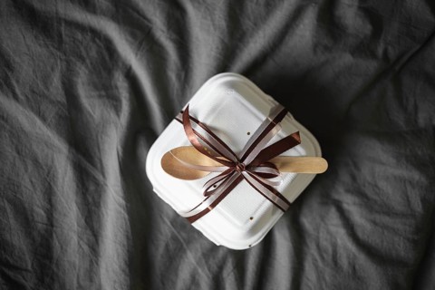 Top view of an elegantly wrapped bento birthday cake, set in a white takeout box with a brown