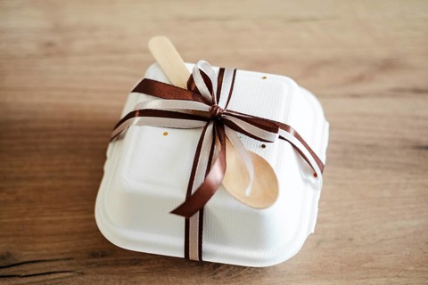 Elegantly packaged bento birthday cake in a white takeout box adorned with a chocolate-brown ribbon