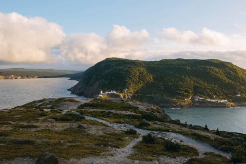 A serene sunset casts warm light over the rugged landscape of Signal Hill, St. John's, showcasing a