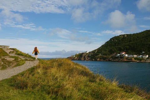 Back view of unrecognizable woman enjoying a serene walk along a coastal trail in Signal Hill, St