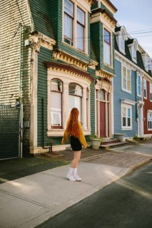Back view of unrecognizable young woman as she walks down a quaint street lined with brightly