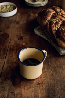 Top view of a freshly baked Bakbah bread garnished with pistachio, alongside a vintage tin cup