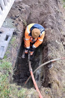 Technician connects fiber optic cable in the ground, Schleswig-Holstein, Germany