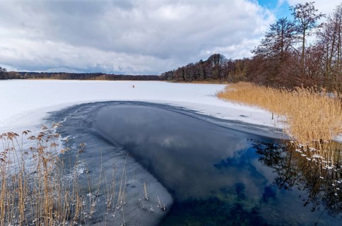 View of the church lake covered with ice and snow in the UNESCO Schaalsee Biosphere Reserve.