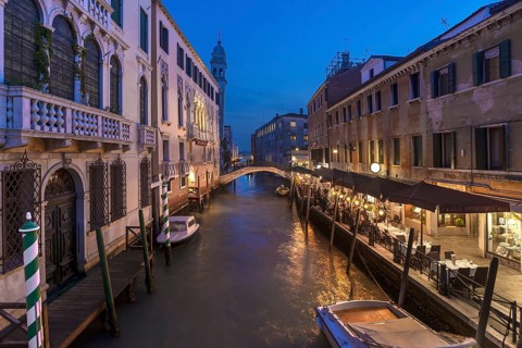 Dinner with restaurant on the canal, in the back the tower of the church of Santa Maria della