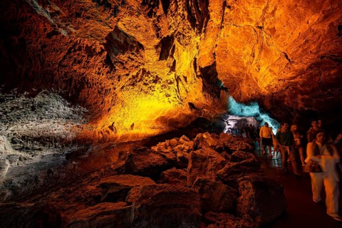 Underground cave formed by lava flow, visitors illuminated lava cave, Cueva de los Verdes,