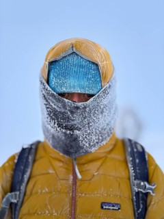 Young man wearing thick winter clothes, down jacket and scarf, with frozen snow in cold weather,