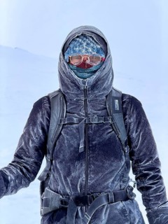 Young woman wearing thick winter clothes, down jacket and scarf, with frozen snow in cold weather,
