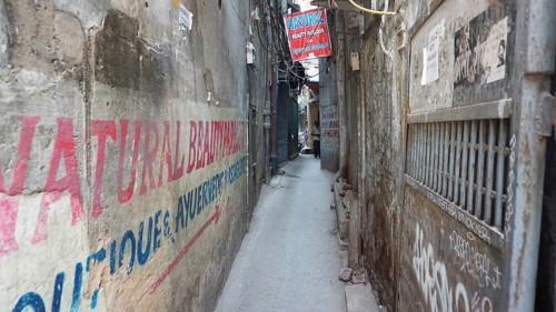Narrow urban alley with colorful advertising banners and graffiti on the walls, Delhi, India