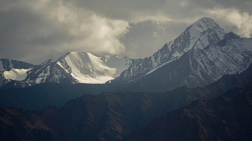 Snowy mountain peaks under a dramatically cloudy sky, trekking in Ladakh, Stok la, Himalayas, India