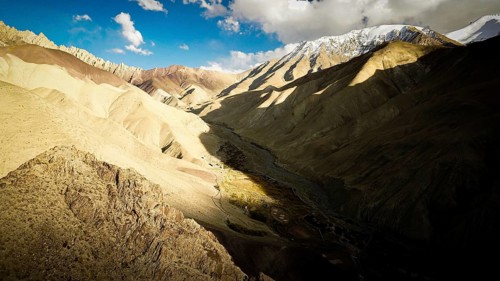 Dramatic mountain landscape with strong light and shadow in the valley, snow-capped mountains in