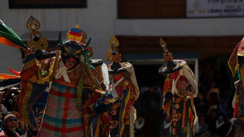 Colourful masked dancers perform a traditional performance in front of an audience, traditional