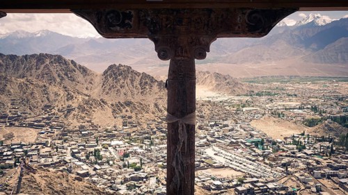 View from a window of the Leh Palace over Leh in a valley with surrounding snow-capped mountains