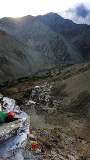 A small village surrounded by mountains in a remote valley under cloudy skies, trekking in Ladakh,