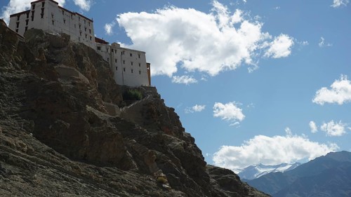 The Leh Palace is majestically perched high up on a rocky mountain with clouds in the bright blue