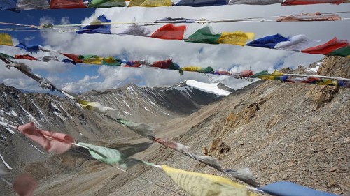 Colourful prayer flags flutter against a high-mountain backdrop, trekking in Ladakh, Stok la,