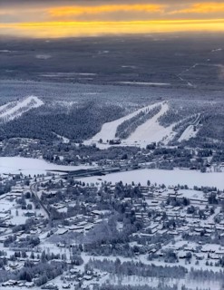 View of the snowy town of Rovaniemi with the Kemijoki river, at sunrise, in winter, aerial view,