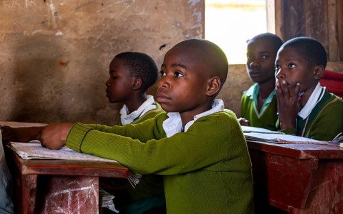 Schoolchildren in school uniform alert during class, sitting at school desks in the classroom,