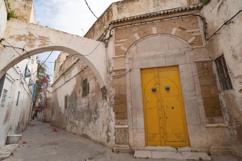 An ornate yellow door of typical Tunisian architecture in the colourful alleyways of the Medina in