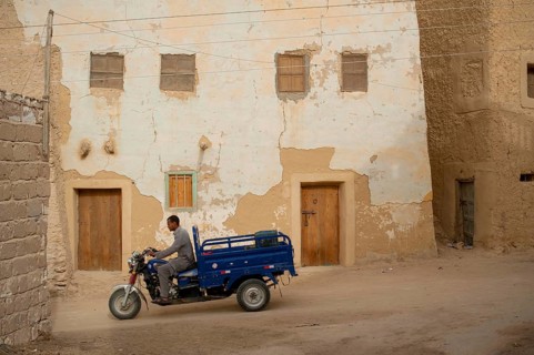 Siwa, Egypt, April 11th 2018 Motorcycle pick-up being driven through the mud brick houses of Siwa