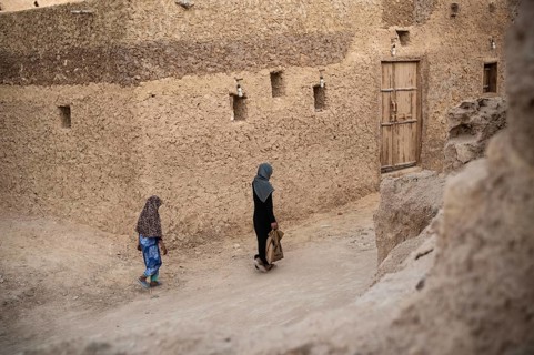 Siwa, Egypt. March 11th 2018 A woman and child walk through the traditional mud brick buildings of